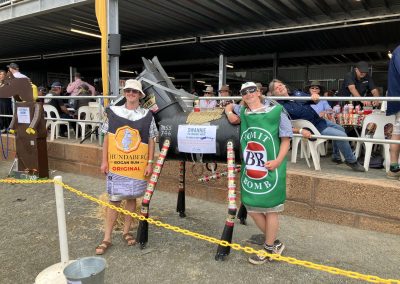 Dog show participants holding banners and trophies at an outdoor event.